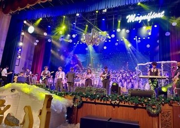 Auf einer bunt beleuchteten Bühne treten viele junge Menschen auf.