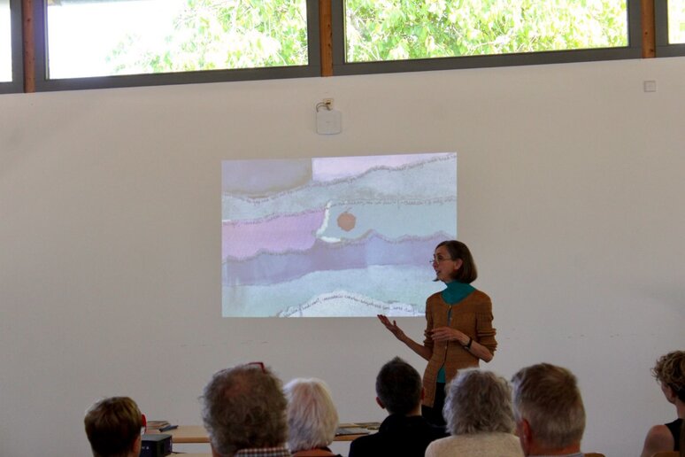 Zuschauer sitzen im Vortragssaal, mit dem Rücken zur Kamera. Diane Samuel trägt vor.