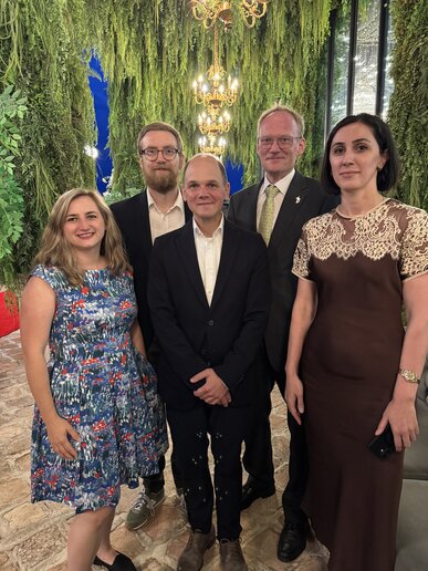 Fünf Personen in festlichen Kleidungen bei einer Feier.