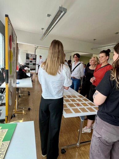 Auf dem Tisch zwischen den Studierenden und Teilnehmenden liegen Karten auf den Symbole wie ein Herz, eine Krone oder auch ein Bett abgebildet sind.