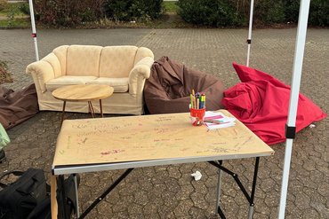 Im Vordergrund steht ein Klapptisch, dahinter ein Sofa und zwei Sitzsäcke.