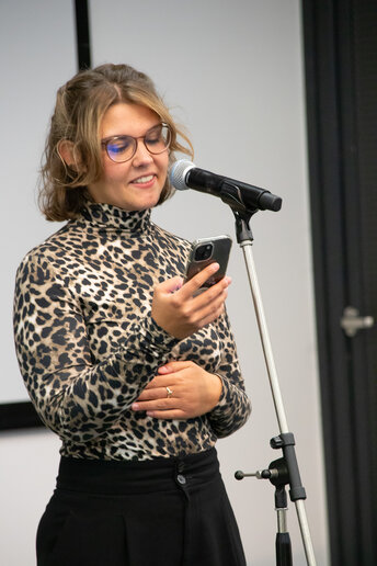 Sophie Lerpscher steht auf der Bühne am Mirko und performt, während sie den Text vom Handy abliest.