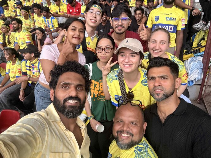 Selfie mehrerer lächelnder Stadionbesucher; im Hintergrund viele Zuschauer, viele tragen gelbe Fußball-Fantrikots.