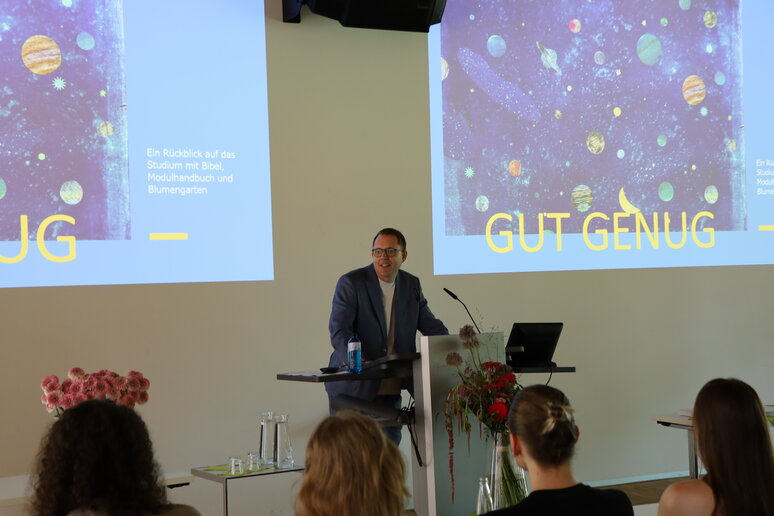 Prof. Dr. Gregor Buß steht am Pult und hält einen Festvortrag. Im Hintergrund erkennt man seine Powerpointfolien.