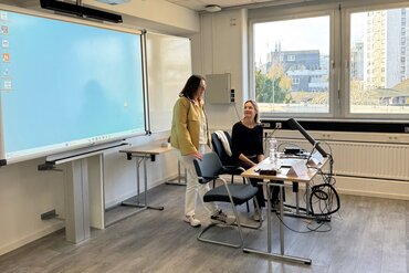 Im vorderen Bereich des Seminarraums stehen Dekanin und Studiengangsleitung und begrüßen die neuen Studierenden.