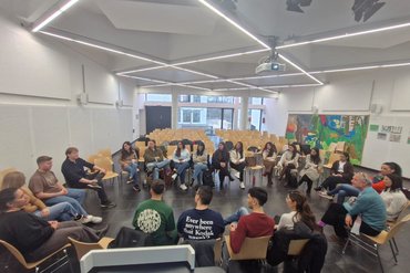 Studierende sitzen in einem Hörsaal zusammen und tauschen sich aus.