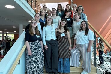 Dozierende und Studierende stehen als Gruppe auf einer Treppe