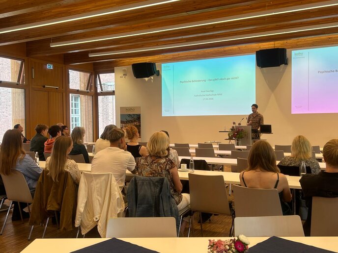 Noel Geerligs präsentiert die Ergebnisse seiner Masterthesis. Er steht auf der Bühne und referiert seine Erkenntnisse. Die Zuschauer_innen hören zu.