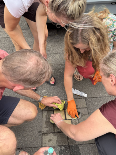 Mehrere Menschen reinigen Stolpersteine