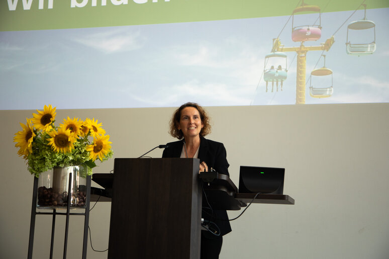 Begrüßungsrede der Dekanin Prof.in Dr.in Anja Kannegießer. Neben ihr steht ein Strauß mit Sonnenblumen.