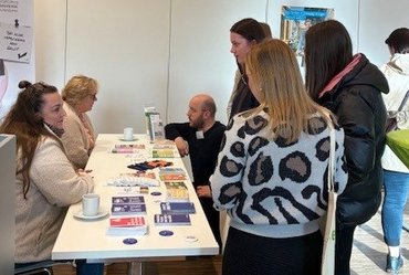 Studieninteressierte stehen vor einem Messestand und lassen sich beraten 