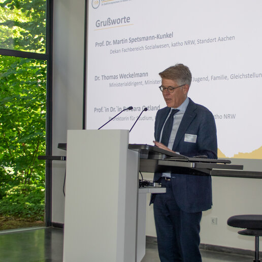 Dr. Weckelmann steht am Rednerpult der Aula.