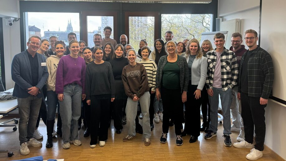 Eine Gruppe Studieninteressierte steht für ein Foto mit Prof. Dr. Oliver Tiemann zusammen und lächelt in die Kamera..
