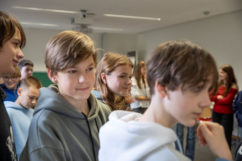 Schüler:innen schauen sich die mit Kohle gemalten Bilder der Mitschüler:innen an.