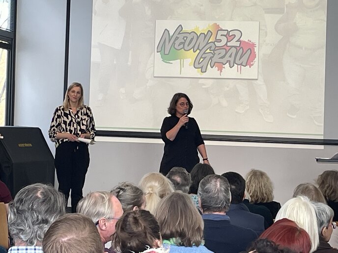 Die beiden Vorsitzenden stehen auf der Bühne und halten eine kurze Ansprache.