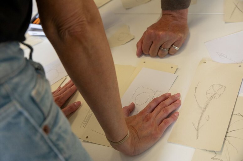 Menschen schauen auf einen Buchstaben sowie weitere Zeichnungen.