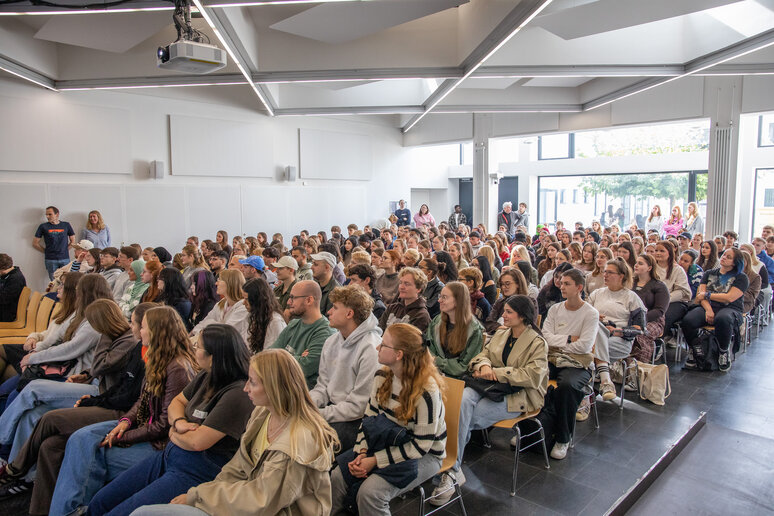 Erstsemester sitzen bei der Begrüßungsfeier in der Aula