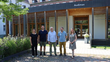 Gruppenfoto von zwei Frauen und drei Männern vor dem Audimax der katho am Standort Paderborn