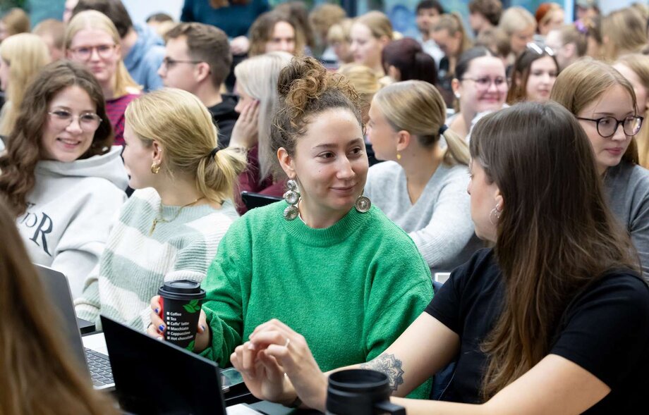 Zwei Studierende unterhalten sich in einem Hörsaal.