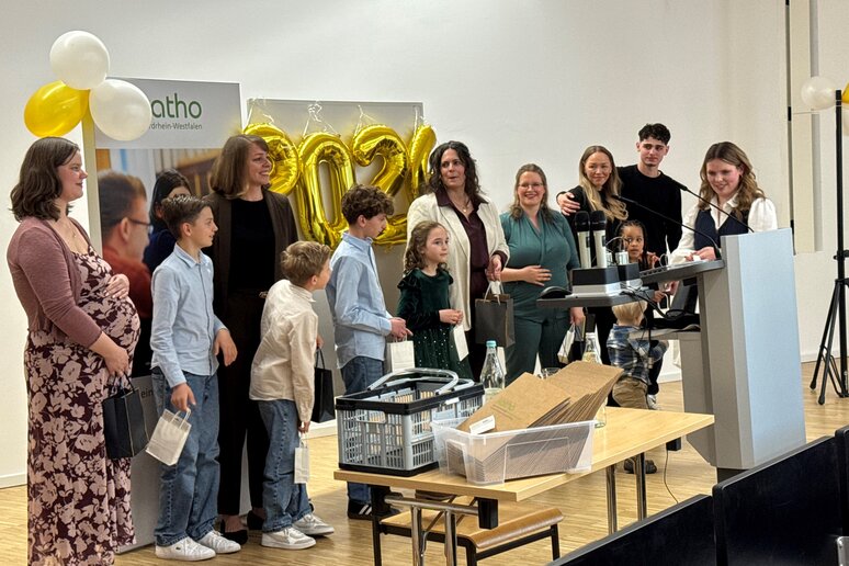 Alle Absolventinnen, die bereits Kinder haben, stehen aufgereiht und erhalten Präsente