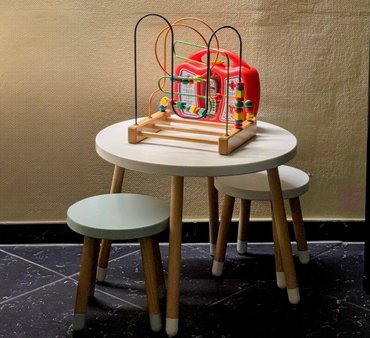 Auf einem Kindertisch mit zwei Hockern steht Spielzeug.