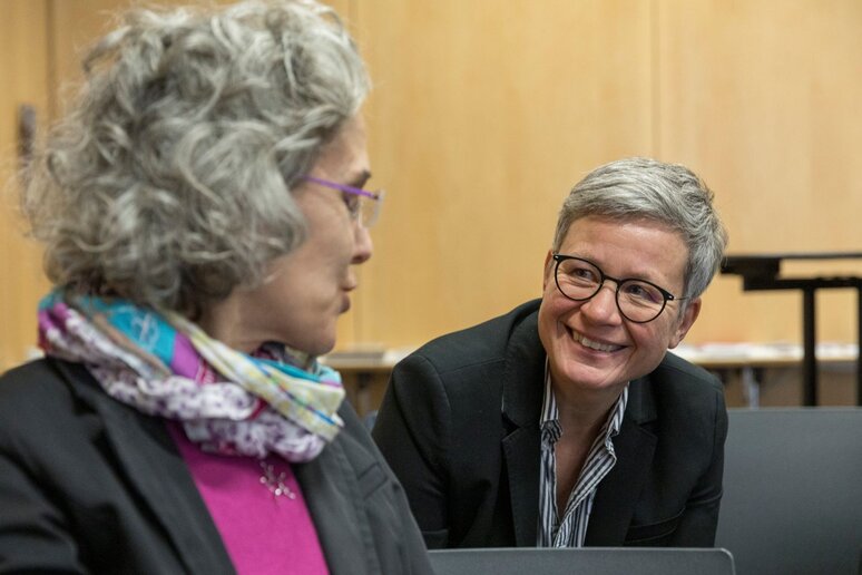 Zwei Frauen sprechen miteinander. Eine Frau lehnt sich nach vorne in Richtung der anderen Frau.