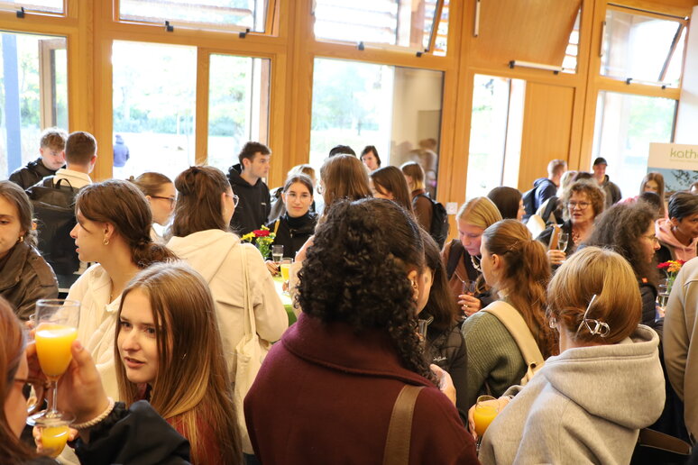 Zhlreiche Studierene stehen - teilweise mit Gläsern in der Hand - dichtgedrängt im Audimax.