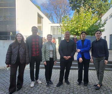 Sechs Personen stehen aufgereiht vor dem Gebäude in Aachen, vor einer Treppe. Sie lächeln in die Kamera.