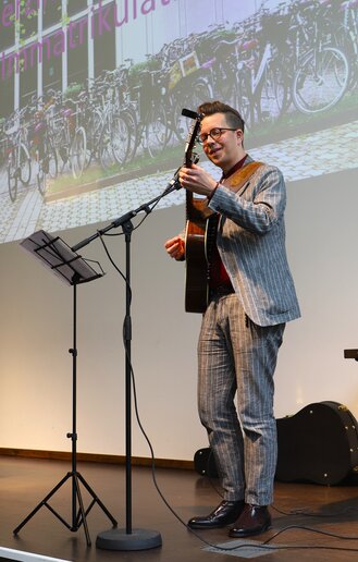 Ein Professor spielt auf der Gitarre und singt dazu.