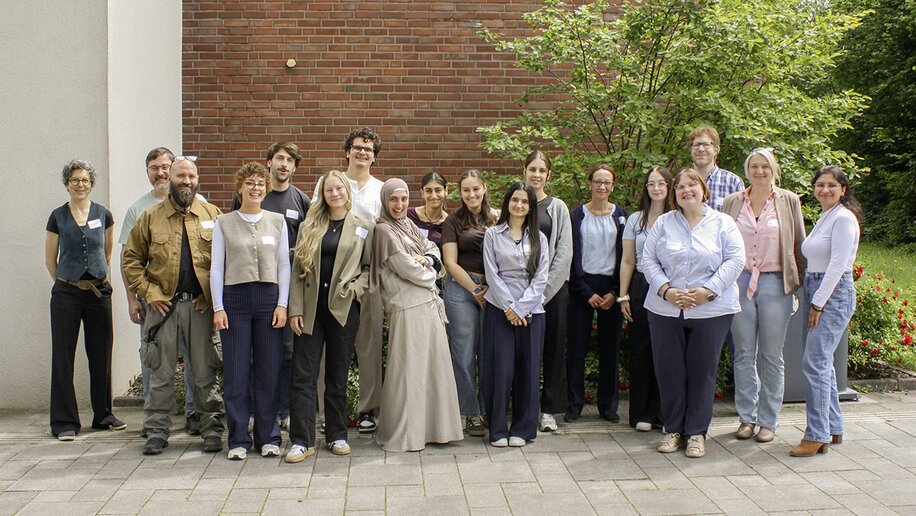 Gruppenbild mit 18 Studierenden und Projektmitarbeitenden, draußen vor einer gemauerten Wand.