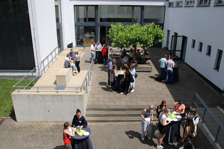 Tagungsteilnehmende versammeln sich im Innenhof der katho