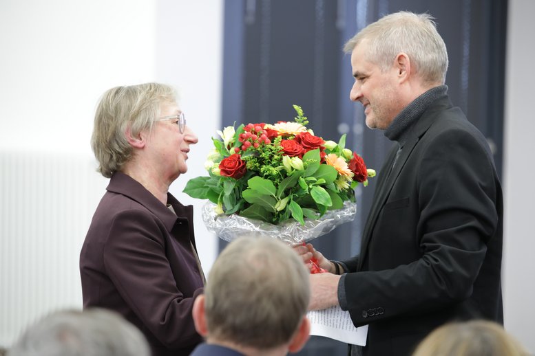 Der Dekan übergibt Liane Schirra-Weirich einen Blumenstrauß