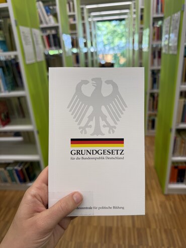 Auf dem Bild sieht man, dass jemand das Grundgesetz (Buch) hochhält.