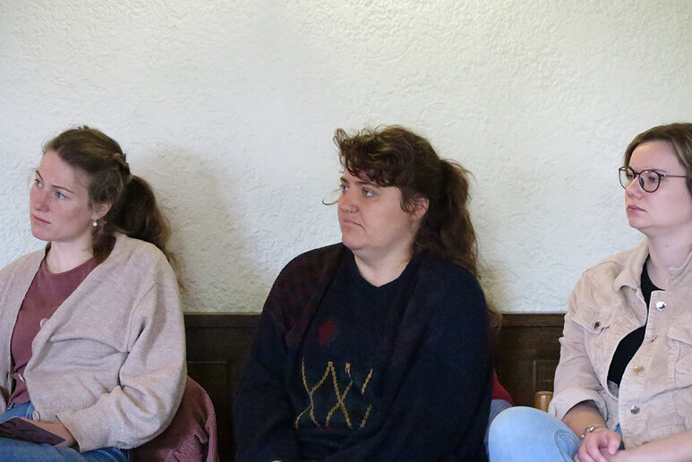 Drei Frauen sitzen nebeneinander und schauen alle nach links außerhalb des Bildes.