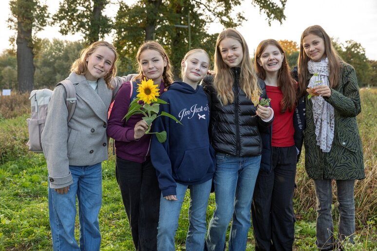 Sechs Schülerinnen stehen aufgereiht für ein Foto auf einer Wiese. Eine hält eine Sonnenblume ins Bild.