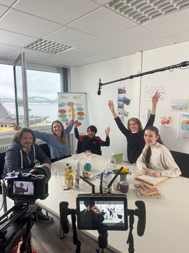 Jubelnde Menschen sitzen rund um einen Tisch.