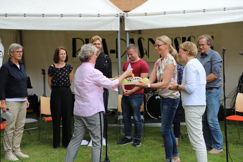 Eine Frau überreicht Frau Paß ein Geschenk.
