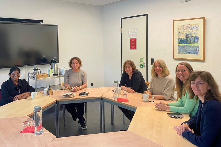 Sechs Frauen sitzen zum Gespräch an einem runden Tisch am Standort Münster.