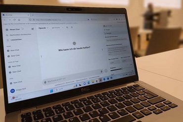 Ein geöffneter Laptop steht in einem Seminarraum. Auf dem Bildschirm ist LibreChat zu sehen.