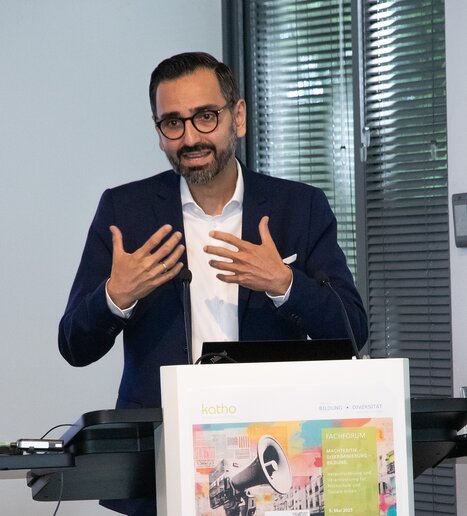 Karim Fereidooni steht am Rednerpult, er gestikuliert mit den Händen.