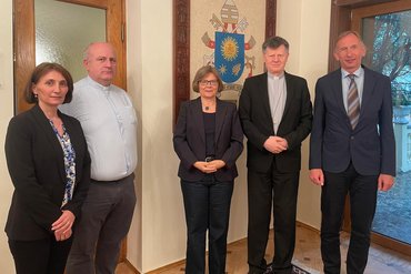 Fünf Personen stehen in einem Raum für ein Gruppenfoto.