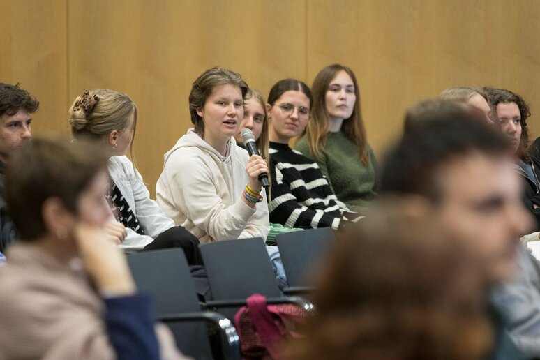 Eine junge Person  aus dem Publikum hat das Mikrofon.