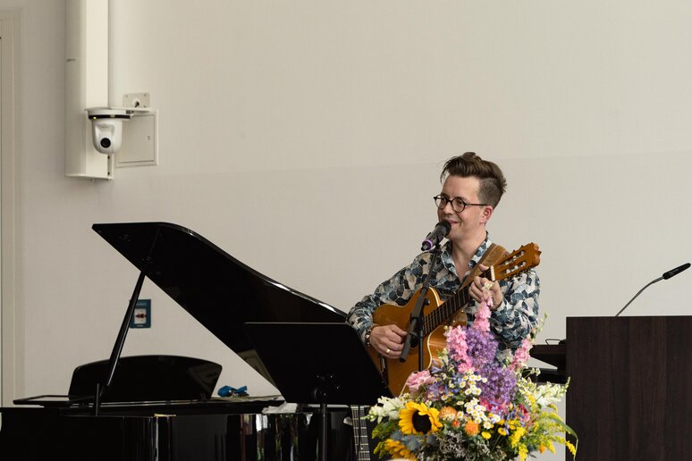 Ein junger Kollege singt gut gelaunt ein Lied und begleitet sich auf der Gitarre.ut gelaunt ei