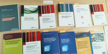 Auf einem Tisch liegen Fachbücher aus; viele der Titel beinhalten "Soziale Arbeit".