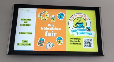 Bildschirm an der Wand auf dem für das Faire Frühstück 