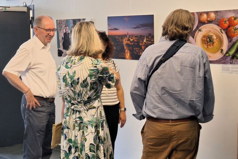 Vier Personen stehen vor großformatigen Fotografien, drei von ihnen sind miteinander im Gespräch.