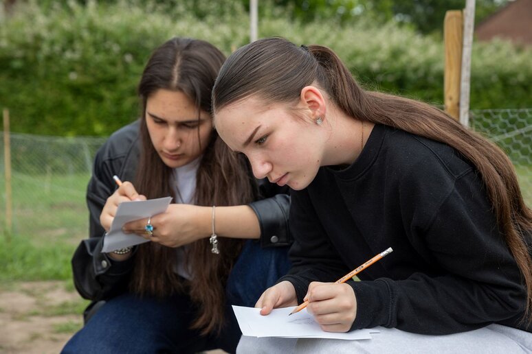 Zwei Personen sitzen in der Hocke und zeichnen etwas nach.