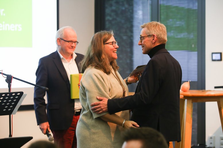 Silvia Hamacher und Christof Stock gratulieren Andreas Reiners auf der Bühne.