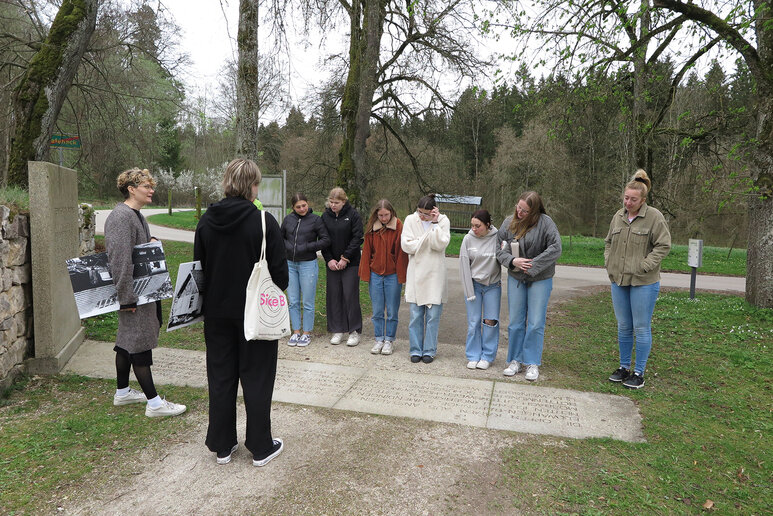 Eine Gruppe Menschen schaut sich Gedenktafeln auf dem Boden an.