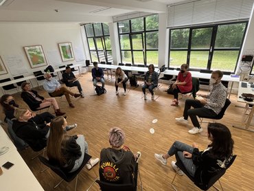 Auf dem Foto sitzen 13 Studientagteilnehmer im Kreis und unterhalten sich.